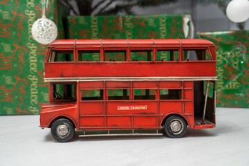 London Double-decker bus toy on a white surface with green gift boxes in the background