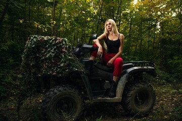 Caucasian white blonde woman on the quad bike in the green forest