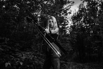 Young woman holding bow and arrow in a forest