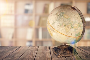 An old retro globe on the table on bookcases background