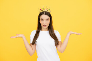 Young woman queen wear golden crown, isolated yellow studio background. Dreamy girl with crown.