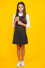 Teenager girl holding a hot cup of coffee or tea. Child with takeaway cup on yellow background, morning energy drink beverage.