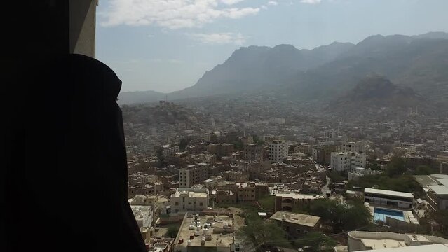 A sad woman looks at the besieged city of Taiz since the beginning of the war in Yemen