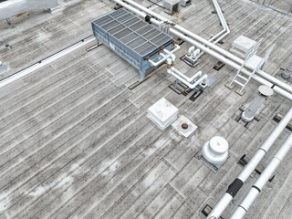 Aerial view of an Industrial looking HVAC equipment and pipes on gray roof.