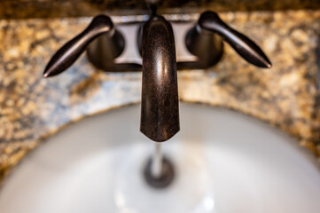 Top down view above a bathroom faucet with water pouring into the sink. 