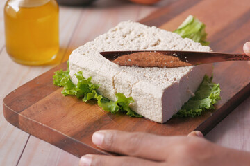 cutting slice of tofu on a chopping board on table 