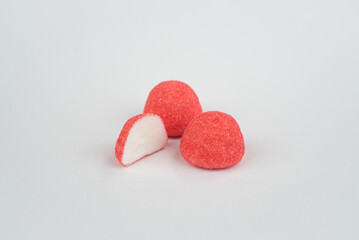 trois bonbons fraises dont un bonbon coupé en deux sur fond uni clair