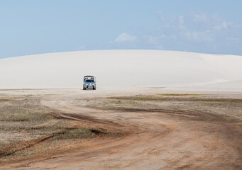 offroad car on the  white dunes filled with rain water of Lencois Maranhenses