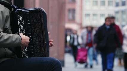 Man playing accordion by the side of the Crowded Street