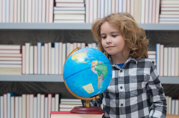 School pupil looking at globe in library, geography lesson. School and kids. Cute blonde child with a book learning. Knowledge day.