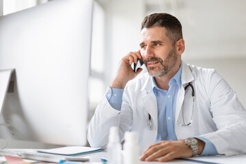 Happy male doctor having phone conversation with patient, sharing good checkup results or giving healthcare consultation