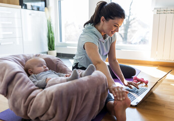 Pretty mother exercising at home while baby sleeping