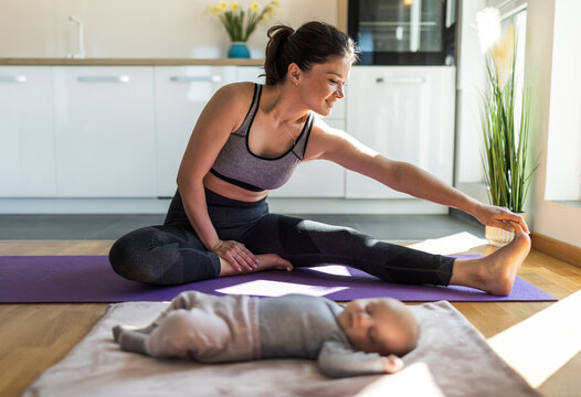 Pretty mother exercising at home while baby sleeping - Powered by Adobe