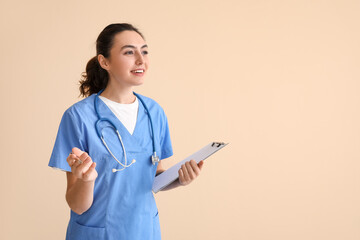 Female medical assistant with clipboard on beige background