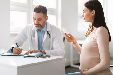 Obraz premium Male doctor rescribing drugs for young pregnant lady, woman holding bottle with pills, therapist explaining prescription