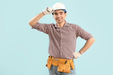 Young carpenter in hardhat on blue background