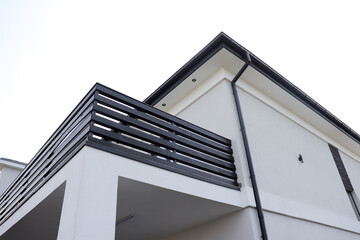 A modern private house with a white facade and a black railing on the balcony. The clean design and sharp lines give the home a sleek, minimalist and contemporary look.