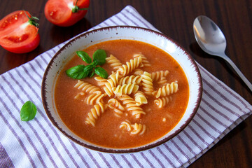 Tomato soup with noodles and basil leaves

