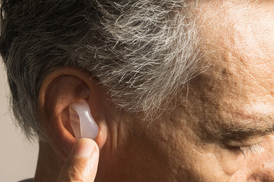 Older Man using custom made silicone earplugs for hearing protection 