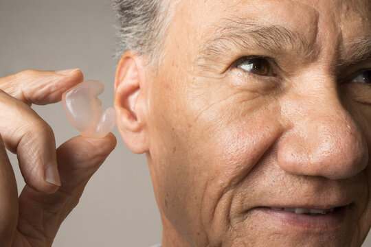 Older Man using custom made silicone earplugs for hearing protection 