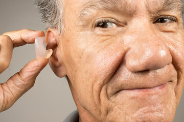 Older Man using custom made silicone earplugs for hearing protection 