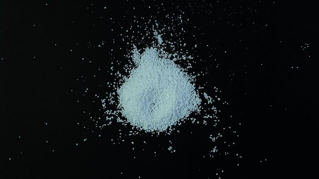 Pile of Sodium benzoate, sodium salt of benzoic acid on dark surface. White crystalline powder, chemical formula C6H5COONa. Food additive E211, Food Preservative also used in medicines and cosmetics.