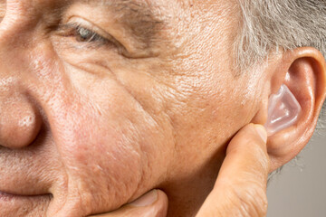 Older Man using custom made silicone earplugs for hearing protection 