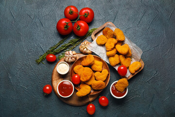 Tasty nuggets with ketchup and vegetables on dark background