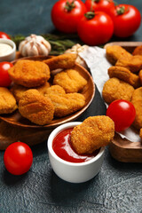 Bowl of tasty ketchup with nuggets on dark background