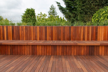 Wood fence cladding and decking, garden greenery on the background