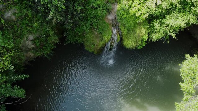 Scenic nature of beautiful wild waterfall and emerald pool of fresh water lake in jungle forest environment. Tropical nature with sun light shining through tree branches. Travel touristic destination.