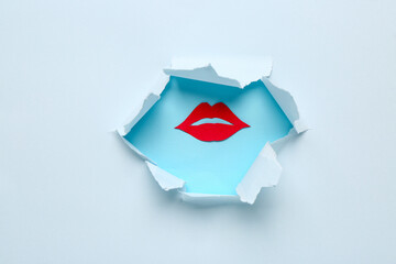 Red paper lips visible through hole in blue paper