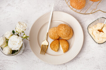Plate with tasty choux dessert on light background