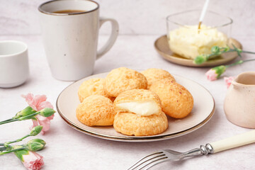 Plate with tasty choux dessert on light background