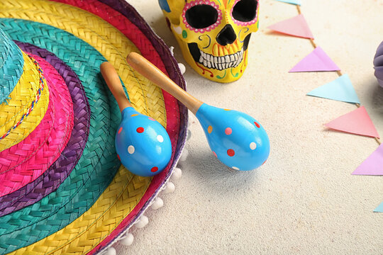 Mexican maracas with sombrero hat, painted skull and flags on white background, closeup