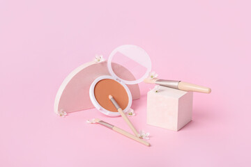 Decorative plaster podiums and cosmetic brushes with powder on pink background