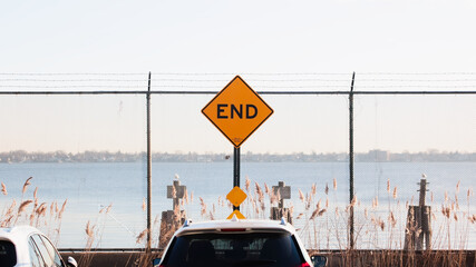 Symmetrical END of the road sign with fence and barbed wire at the sea shore