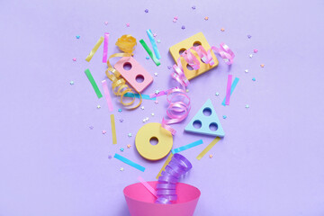 Party cone with baby blocks, confetti and serpentine on lilac background. Children's Day celebration