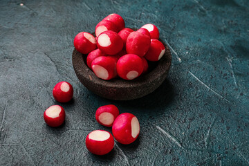 Bowl with fresh radish on dark background