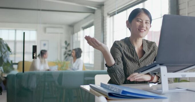 Happy asian casual businesswoman having laptop video call in office in slow motion