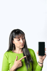 Woman with green blouse pointing at smartphone with blank screen on white background