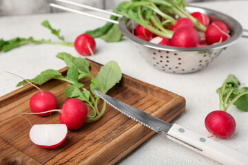 Wooden board of ripe radish with green leaves on table