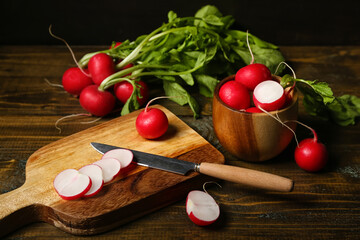 Bowl and wooden board of fresh cut radish on table