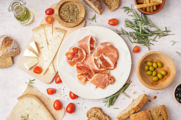 Plate with tasty jamon slices on light background