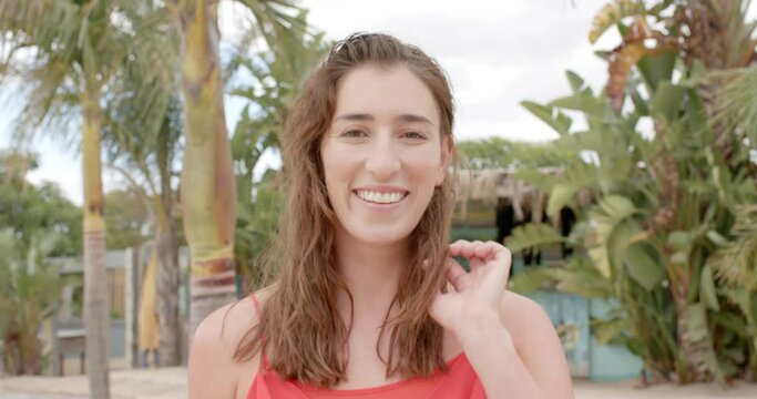 Portrait of happy caucasian woman looking at camera over palm trees