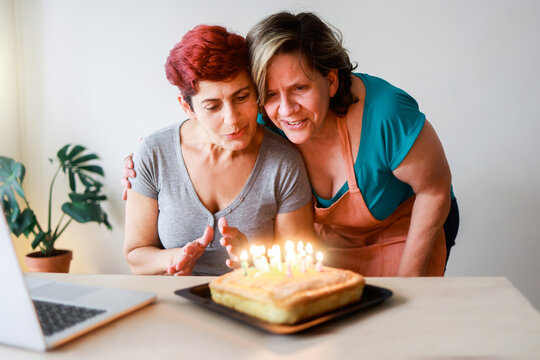 Senior gay lesbian couple birthday party - Wives celebrating anniversary with surprise cake at home - Lgbt family love - Powered by Adobe