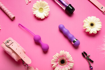 Sex toys with flowers on pink background
