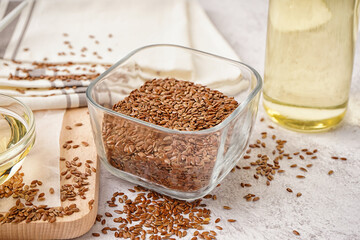 Bowl with flax seeds on light grunge background