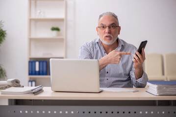 Old male employee working at workplace