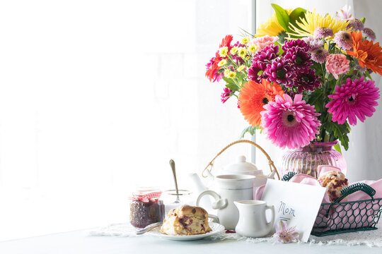A beautiful Mother's Day arrangement with tea, scones and a bouquet of flowers.